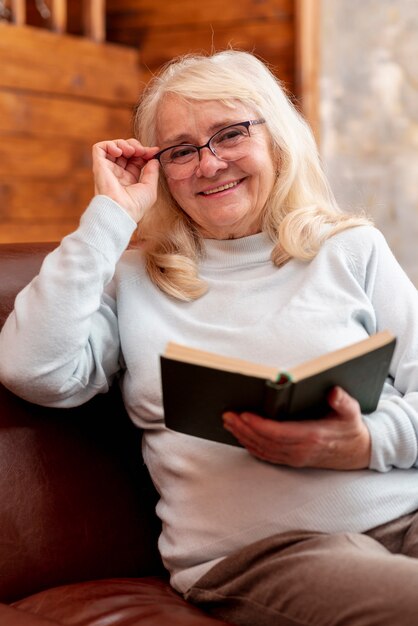 Улыбающаяся старшая женщина читает дома