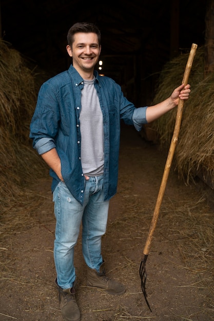 Foto gratuita pastore sorridente con vista frontale del forcone