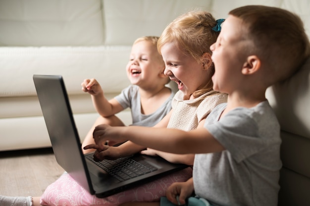 Smiley siblings at home watching on laptop