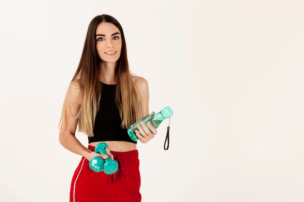 Smiley sport girl with her bottle and dumbbells