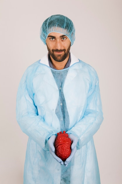 Free photo smiley surgeon holding a heart