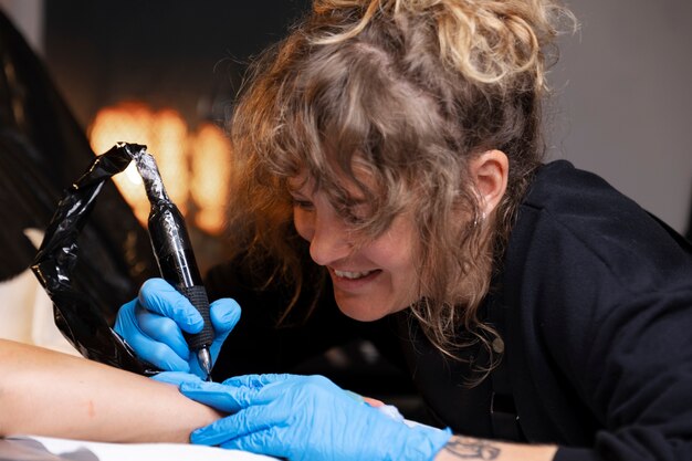 Smiley tattoo artist working side view