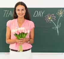 Free photo smiley teacher holding a bouquet of flowers