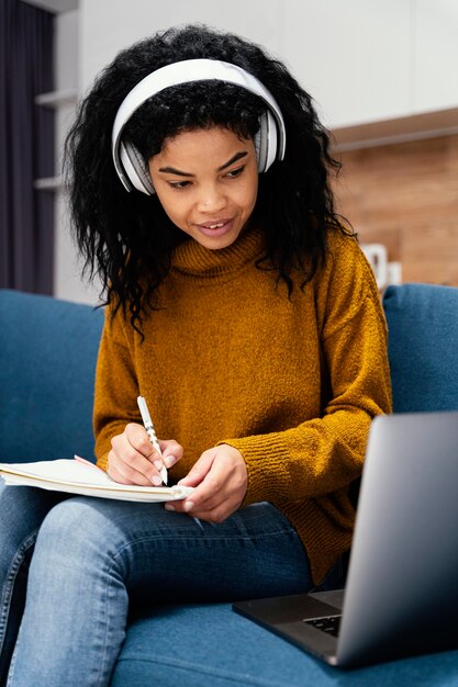 Smiley teenage girl with headphones and laptop during online school