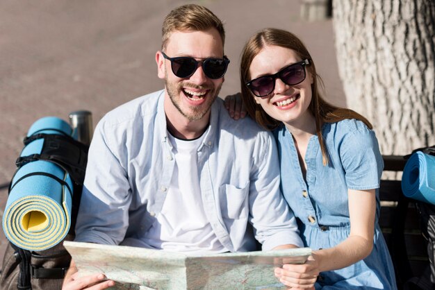 Smiley tourist couple holding map