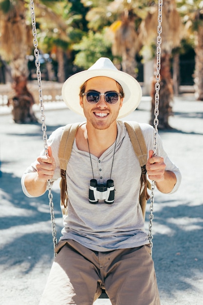 Free photo smiley tourist posing on the swing