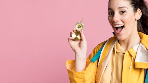 Free photo smiley traveler woman using a compass with copy space