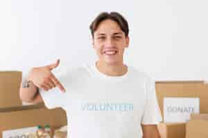 Free photo smiley volunteer pointing to his t-shirt