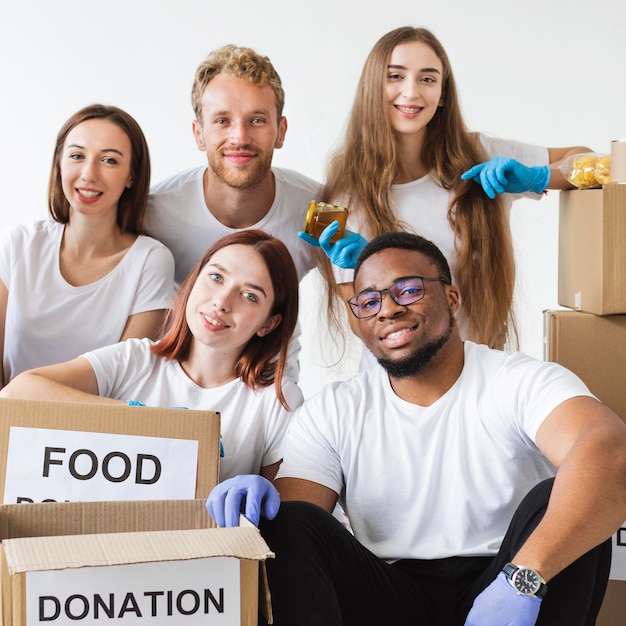 Foto gratuita volontari di smiley in posa insieme a donazioni di cibo