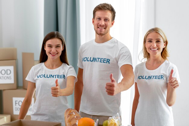 Smiley volunteers posing while giving thumbs up