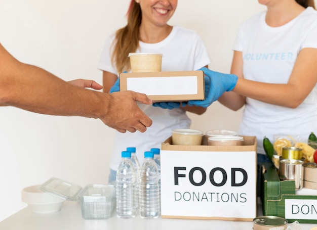 Smiley volunteers with gloves handing boxes with food for donation