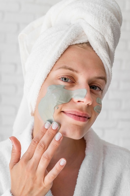 Free photo smiley woman applying face remedy