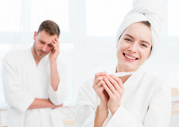 Smiley woman in bathrobe holding bathrobe with concerned man