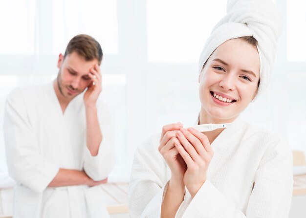 Smiley woman in bathrobe holding bathrobe with concerned man