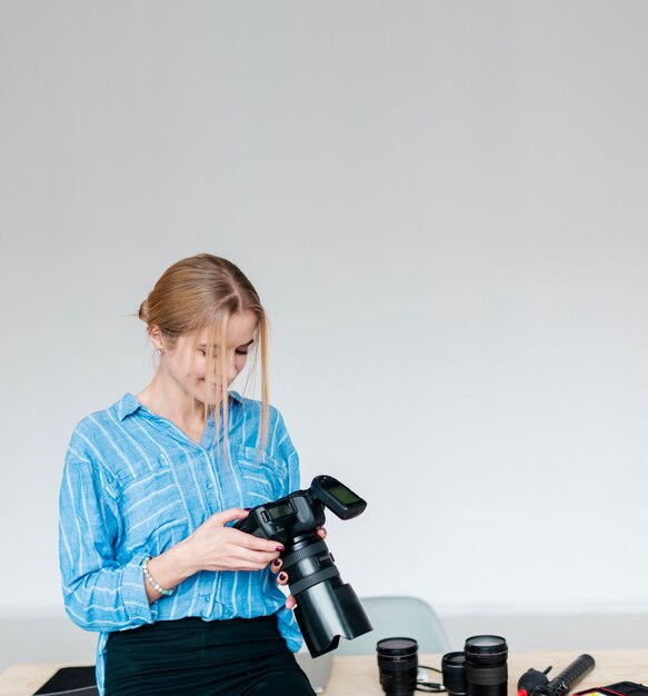 Smiley woman in blue shirt holding a camera and looking down