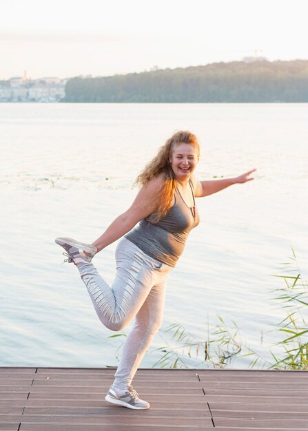 Smiley woman by the lake stretching