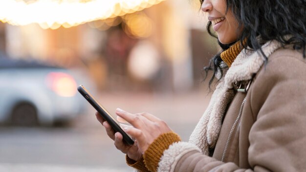 スマイリー女性が屋外で電話をチェック