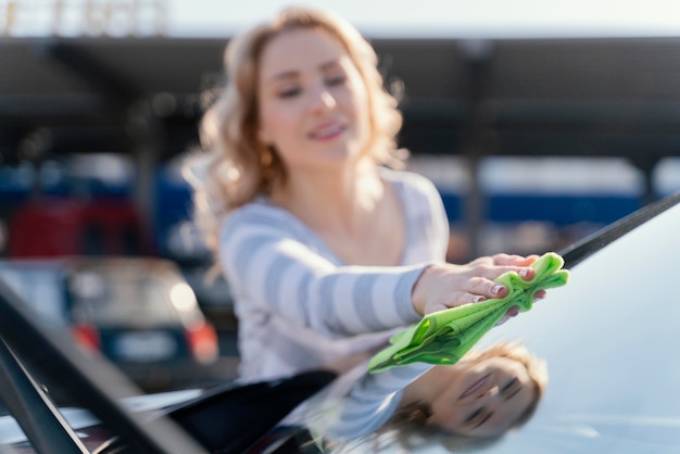 Free photo smiley woman cleaning her car outside