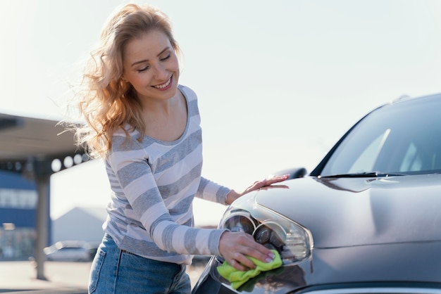 Smiley woman cleaning her car outside