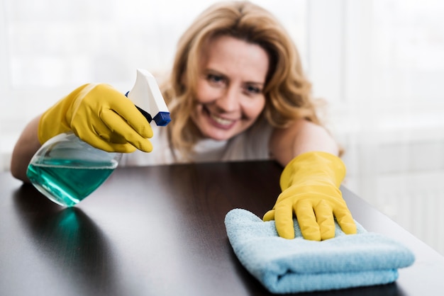 Smiley woman cleaning the table