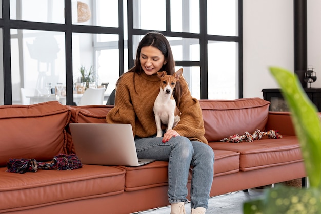 彼女の犬を保持しているソファの上のスマイリー女性