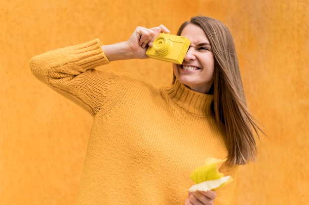 Free photo smiley woman covering an eye with an autumn leaf