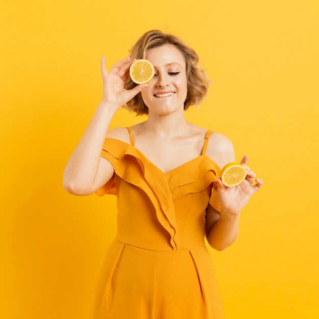 Smiley woman covering eye with lemon slice