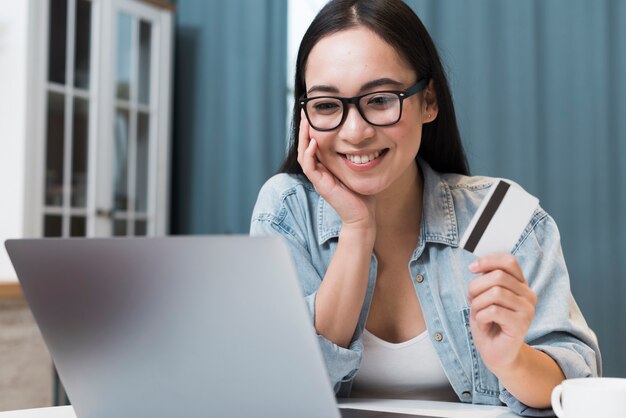 Smiley woman at desk with credit card and laptop