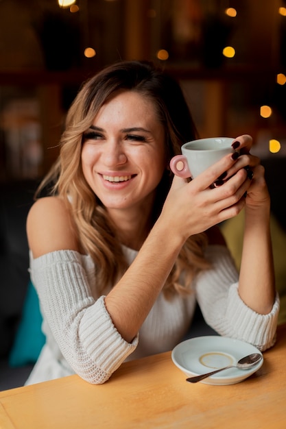 スマイリーの女性がコーヒーを飲む