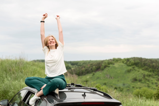 Smiley woman enjoying nature on top of car