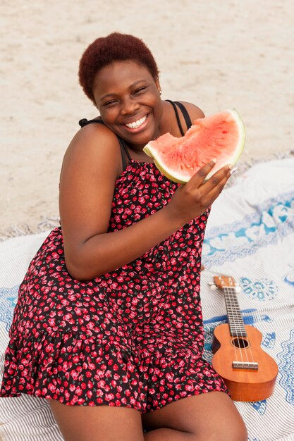 Смайлик женщина, наслаждаясь арбузом на пляже