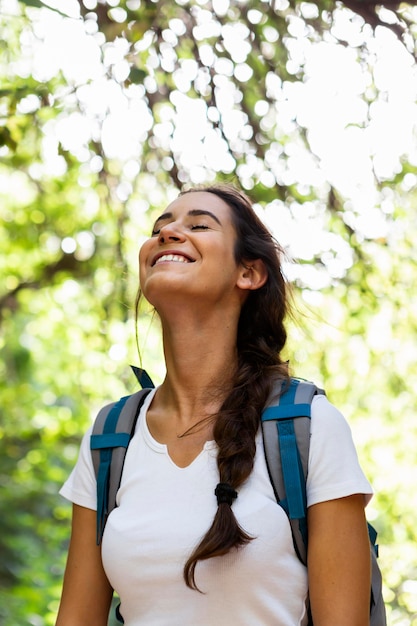 Donna sorridente che esplora la natura con lo zaino