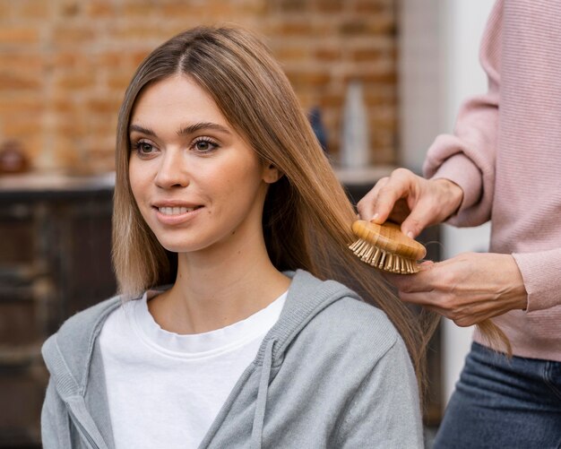 Улыбающаяся женщина расчесывает волосы в салоне красоты