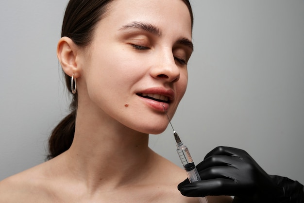 Smiley woman getting lip fillers at clinic