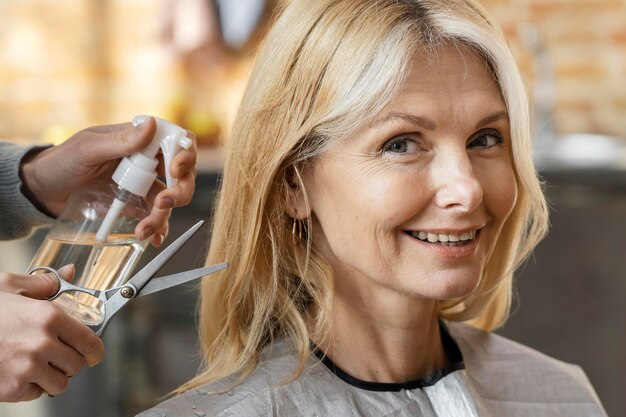 Smiley woman getting ready for a haircut at home with hairdresser