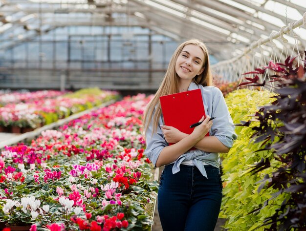 Smiley woman in greenhouse with clipboard