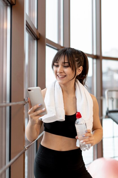 Smiley woman at gym on break using mobile