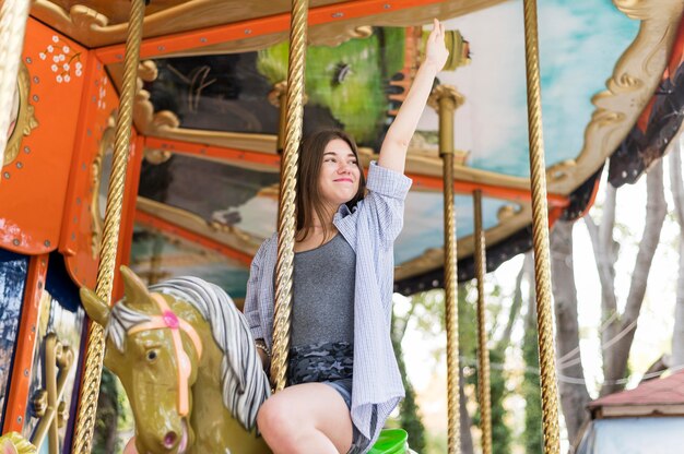 Smiley woman having fun on the carousel