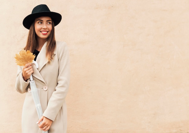 Smiley woman holding an autumnal leaf with copy space