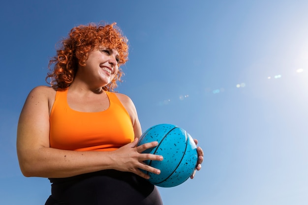 Foto gratuita angolo basso della sfera della tenuta della donna di smiley