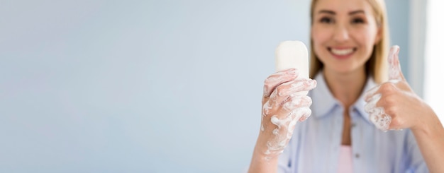 Smiley woman holding bar of soap and giving thumbs up