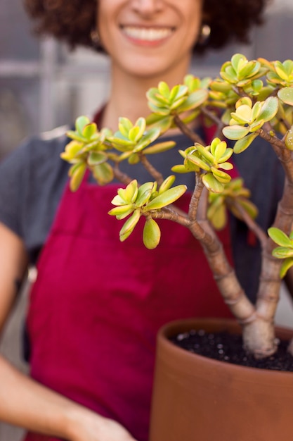 Smiley woman holding a beautiful plant close-up