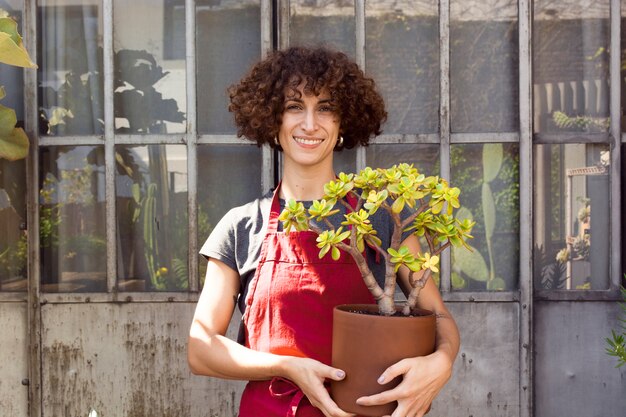 鍋に美しい植物を保持しているスマイリー女性