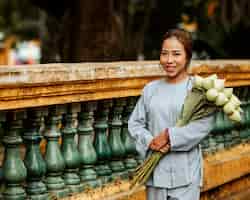 Free photo smiley woman holding bouquet of flowers at the temple