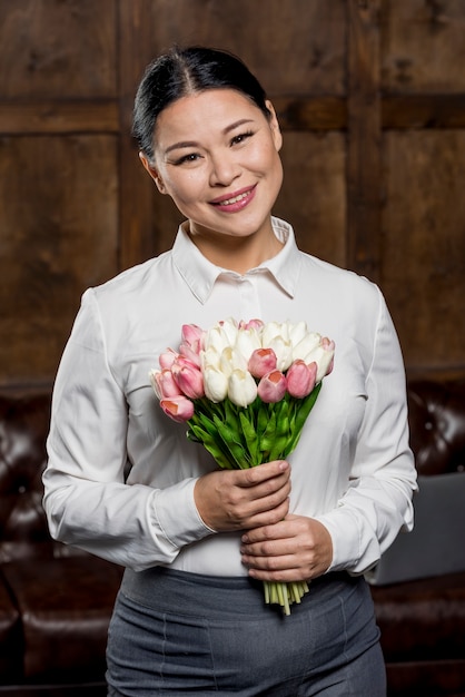 Free photo smiley woman holding bouquet of flowers