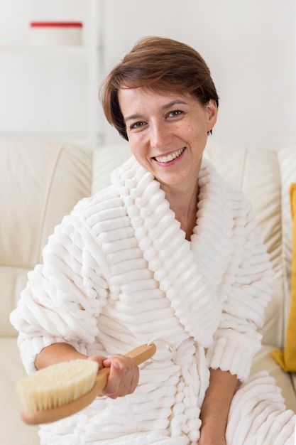 Free photo smiley woman holding a brush spa at home concept