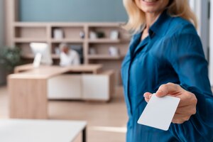 smiley woman holding business card at work