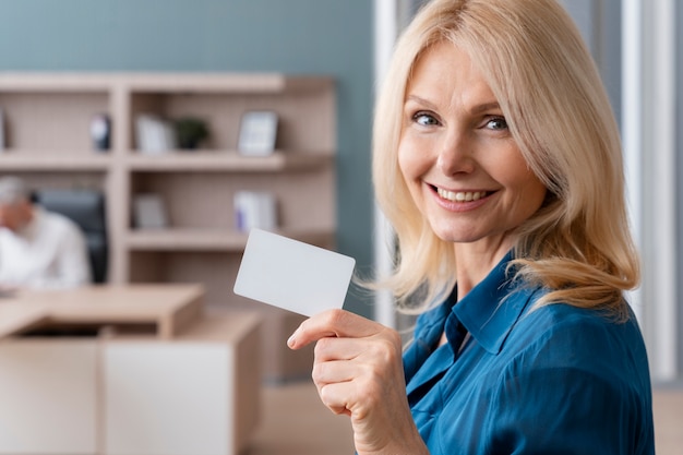 Foto gratuita donna sorridente che tiene biglietto da visita in ufficio