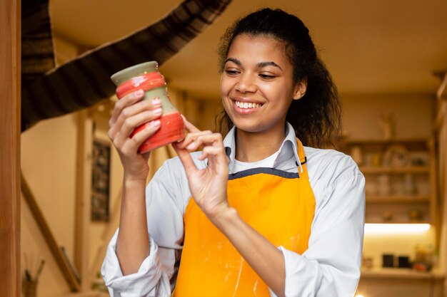 Smiley woman holding clay pot medium shot