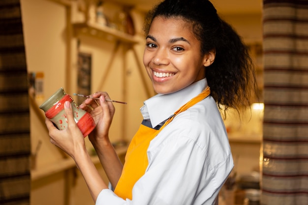 Smiley woman holding clay pot